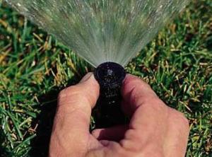 A Lewisville Sprinkler Repair tech adjusts a spray style pop up head by hand