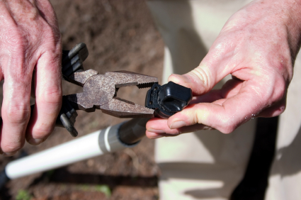 a tech crimps the edge of a pop up head riser to provide a complete seal